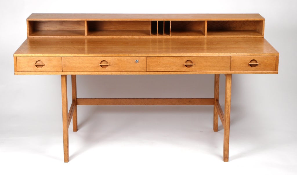 Danish icon desk in oak, full of wood grain. Design often attributed to Jens Quistgaard. 
Brass hinged flip top compartment allows this desk to expand for a partner, into a conference or dining table.