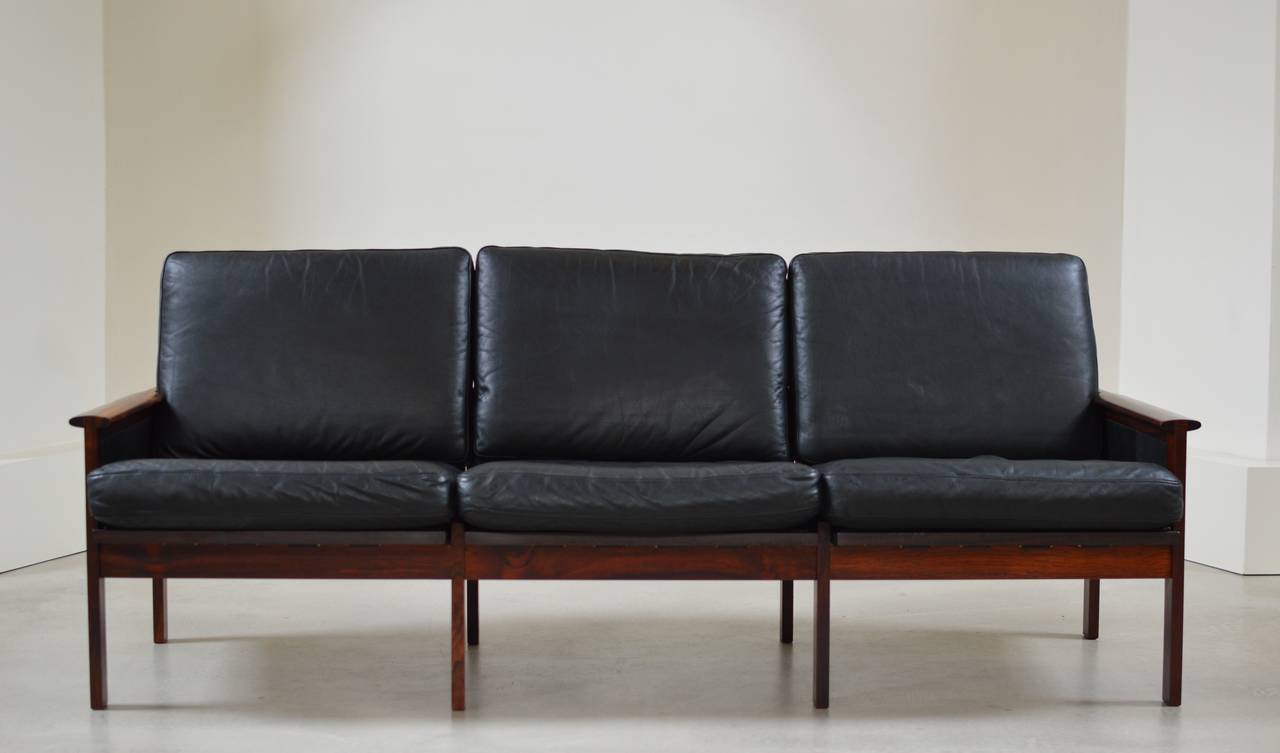 3 seat sofa from the Capella Series designed in 1958 by Illum Wikkelsø for N. Eilersen executed in a beautiful grained Rosewood with black leather loose cushions and wonderful back support structure. 

Please take notice on the exquisite wood