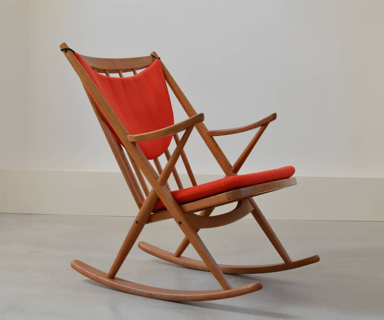 Lovely and very comfy Mid-Century Danish rocker by Frank Reenskaug for Bramin with sculpted arms and spindle back in solid oak with bright red fabric cushions.
