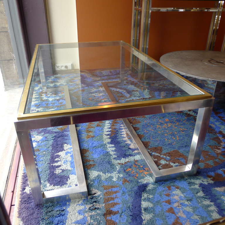 a large chromed metal coffee table with bronze details
and glas tabletop.