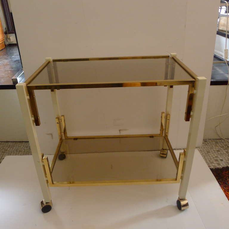 a two tier bar cart with bronze and lacquered ivory white details.