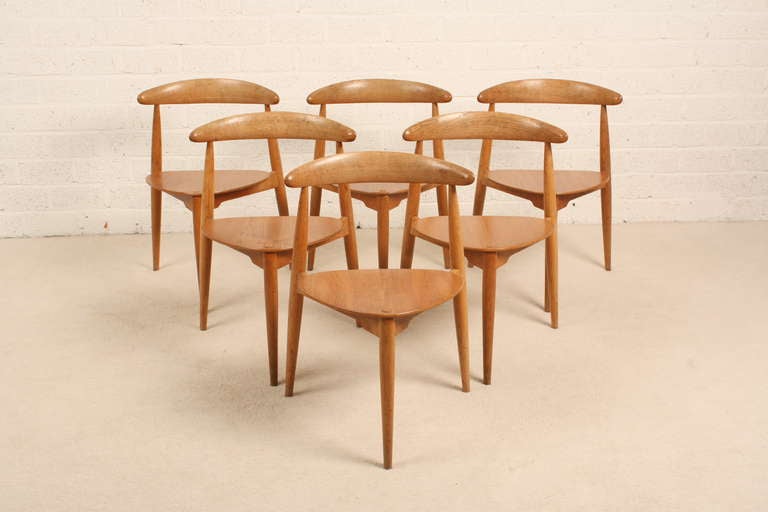 Three legged chairs and three legged table. This is the only way to fit six chairs under one round table. Designed by Hans Wegner in 1950. The chairs are stackable. Wood is oak.