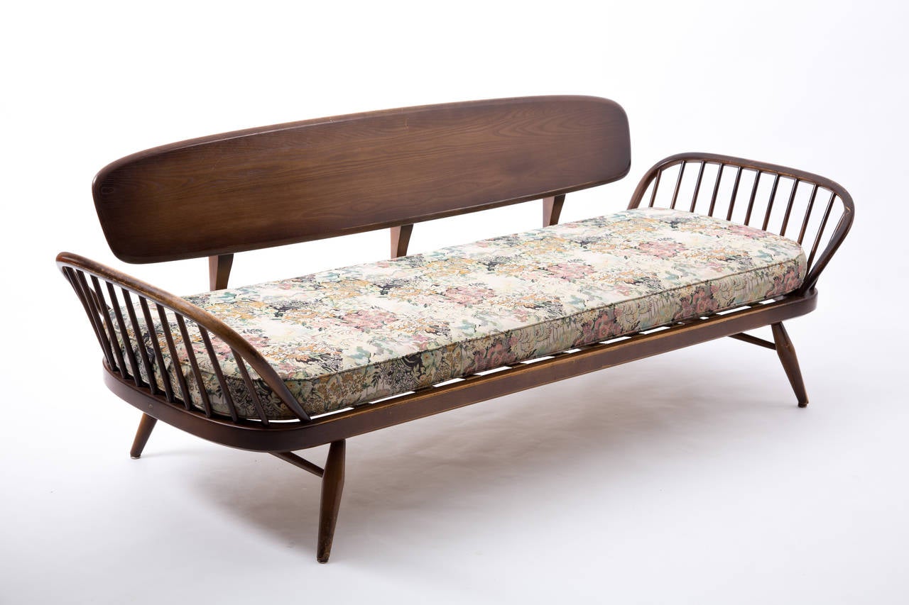 Ercol sofa plus footstool. The frame is of wood and the cushions are of fabric with romantic flowers and nature figures.