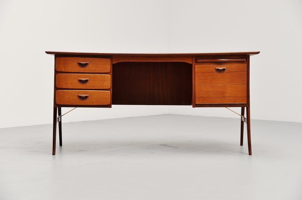 Very nicely shaped writing desk designed by Louis Van Teeffelen for Webe, Holland 1959. This slightly boomerang shaped desk was made of teak and has brass supports underneath the cabinets. On the left there are three drawers and on the right there