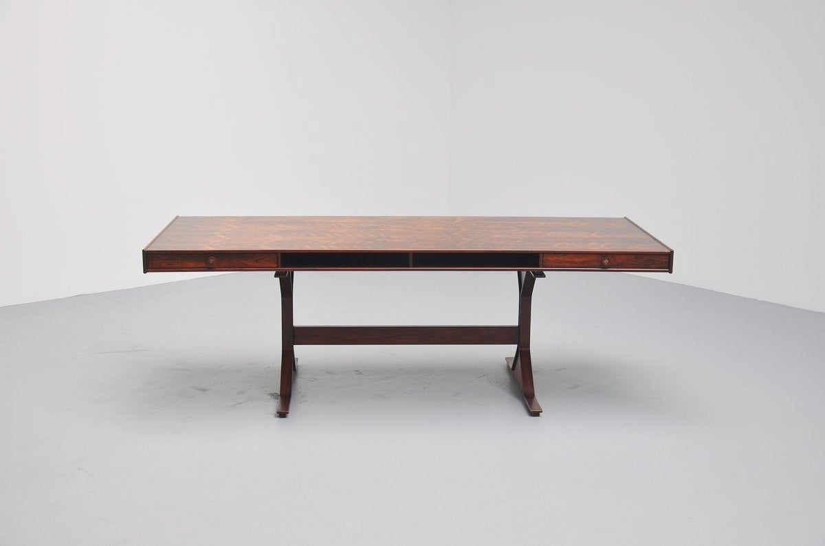 Large rosewood desk designed by Gianfranco Frattini for Bernini, Italy, 1956. This amazing shaped desk is made of rosewood veneer and this has an amazing grain to the wood. The desk has two drawers and storage space in the middle and at the back of