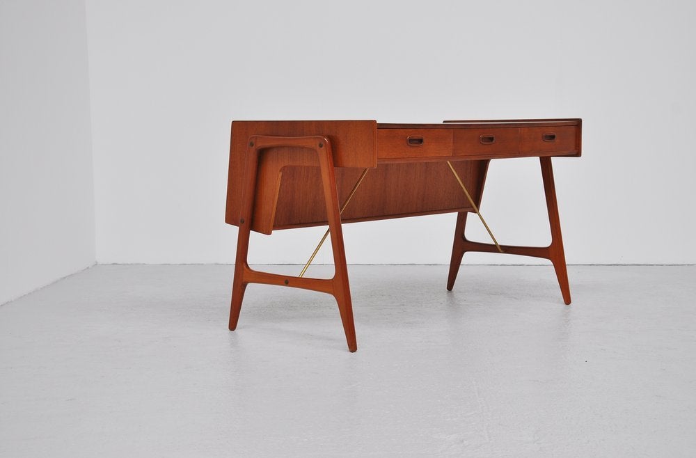 Fantastic organic shaped desk by unknown Danish maker, made in Denmark 1960. This desk has a typical Danish organic shape with very nice brass connections and nice grips. It has 3 drawers upfront and because of the sliding door with bookshelve at