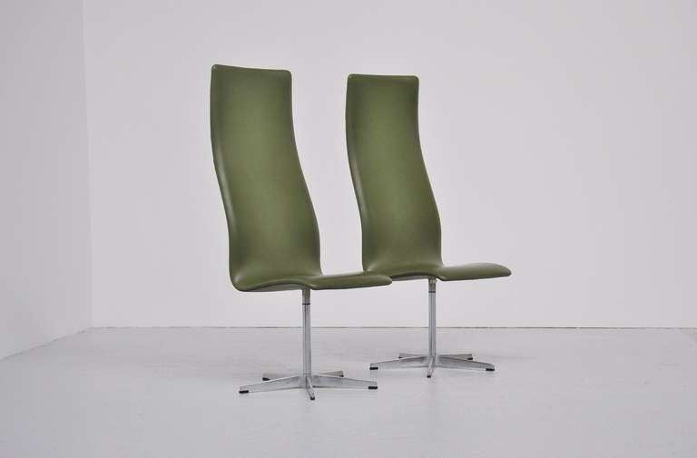 Fantastic pair of high back Oxford chairs by Arne Jacobsen for Fritz Hansen, Denmark 1962. This is for a pair of rare early production chairs with original green vynil upholstery in great shape. The chairs are marked with the Fritz Hansen sticker