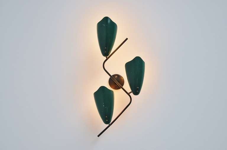 Very nice shaped wall lamp with 3 dark green shades and brass finishing. Unknown maker or designer but probably Italian, maybe French. The lamp gives very nice and warm light when lit and is completely original and working.

All our lights are