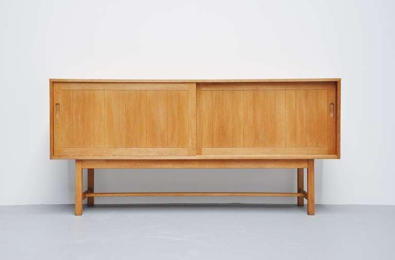 Very nice oak sideboard by Kurt Ostervig for KP Mobler, Denmark 1970. This sideboard has 2 sliding doors and 4 drawers behind on the right. 2 Shelve compartments and very functional. Uncommon height but very subtle looking on the high base. Nice and