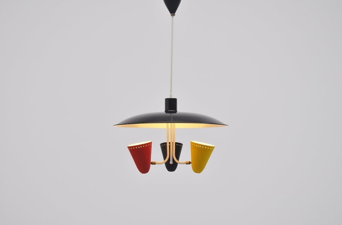 Very nice and typical Dutch 1950s ceiling lamp designed by H. Busquet for Hala Zeist, Holland 1955. This nicely shaped ceiling lamp has a large black lacquered reflector dish with three colored shades underneath in black, yellow and red. The shades