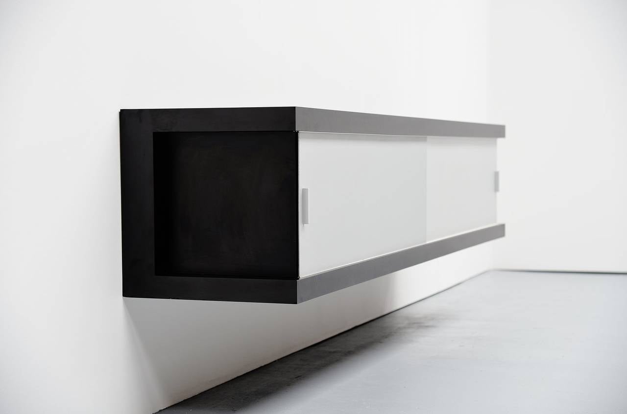 Fantastic floating sideboard designed by Horst Bruning for Behr, Germany 1967. This sideboard was made of black laminated wood and it has two anodized aluminum sliding doors. On the left there are three drawers. The sideboard is very easy to wall