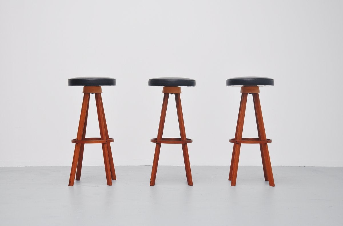 Very nice set of 3 bar stools designed by Frem Rojle, Denmark 1960. These stools have a solid teak wooden base and synthetic black leather seats that swivel. Very nice quality stools and nicely shaped. Comfortable seating and marked underneath the