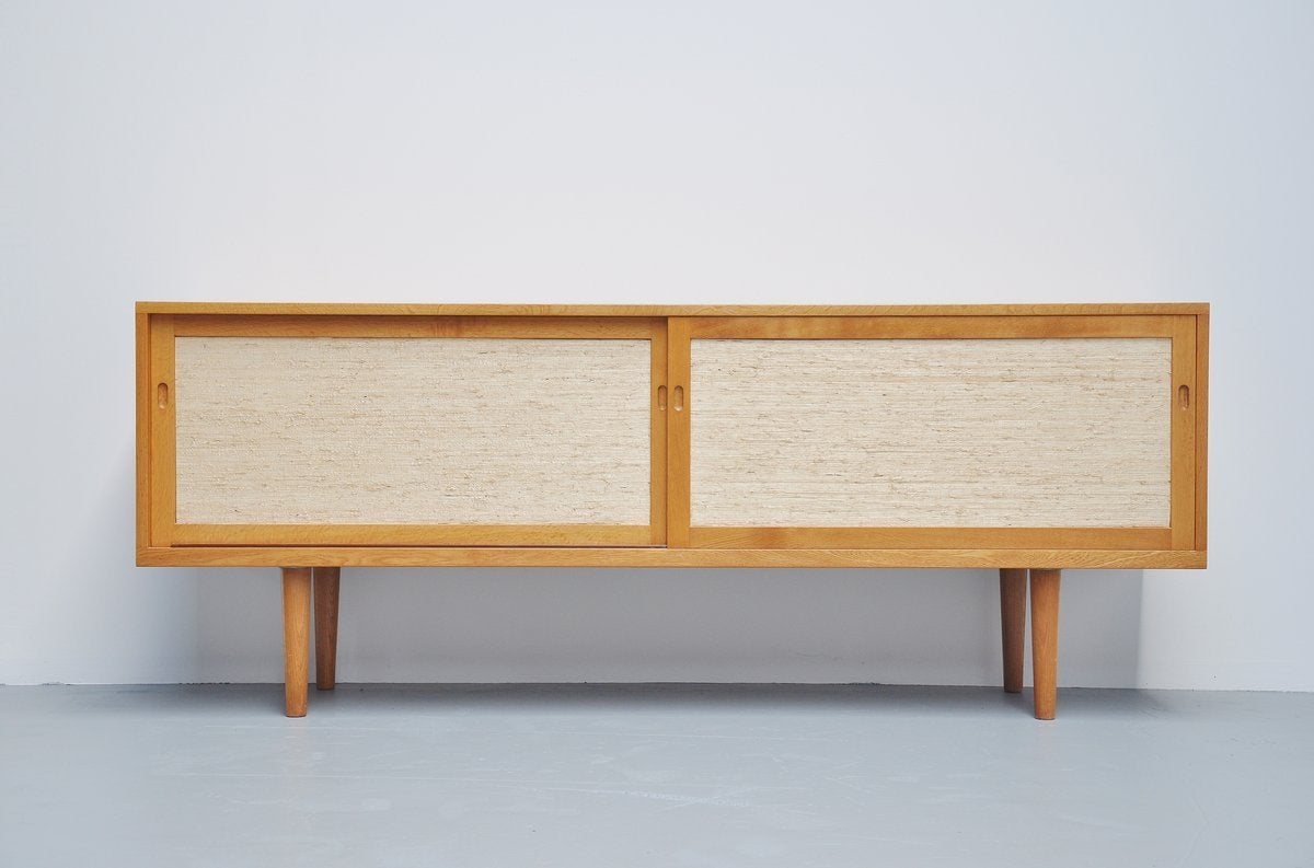 Very nice and typical Wegner refined sideboard, designed by Hans J. Wegner for RY Mobler, Denmark 1965. This is for a very nice oak sideboard with webbing finished sliding doors. Marked with Danish furniture controll tag on the inside. Superb