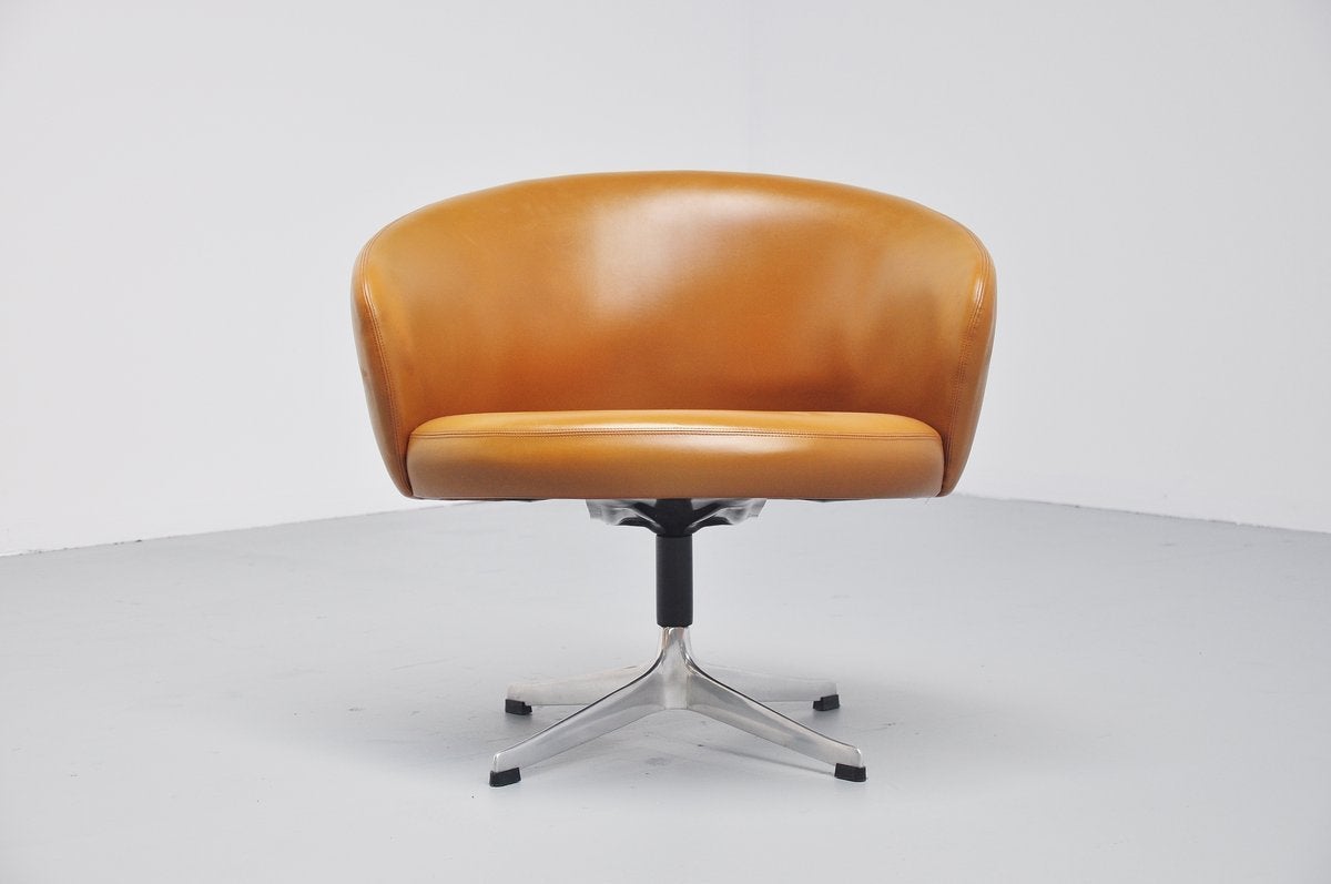 Nicely shaped and rare swivel lounge chair Rondino, designed by Yngve Ekstrom for Swedese, Sweden 1950. This chair has a brushed steel start shaped base with black plastic feet and the upholstery is made of caramel brown vinyl (synthetic leather).