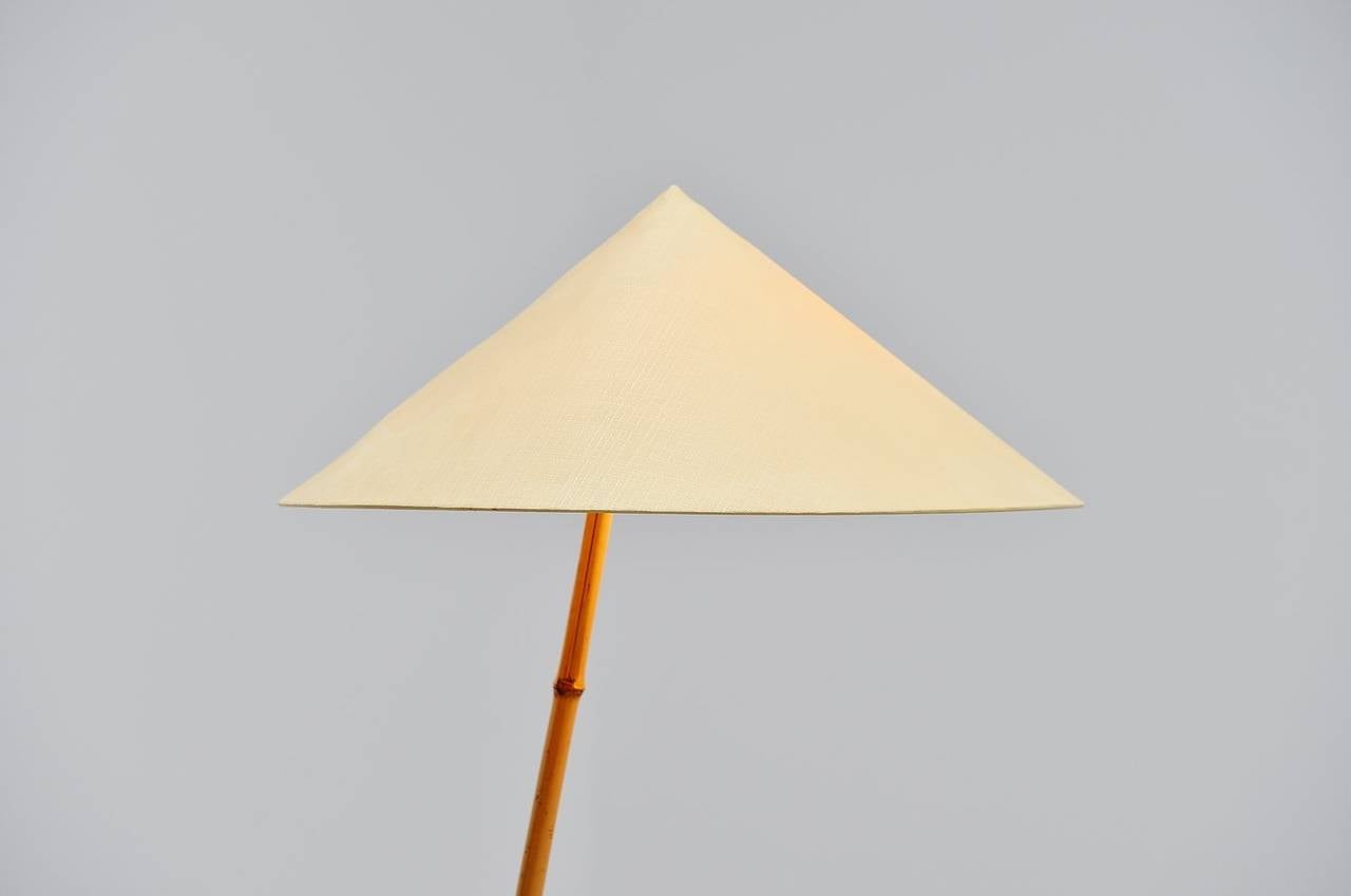 Very nicely made and shaped floor lamp designed and made by Rupert Nikoll, Austria 1950. This early floor lamp has a bamboo and brass foot with a fabric Chinese hat shaped shade. The lamp has a nice large size and gives very nice and warm light when