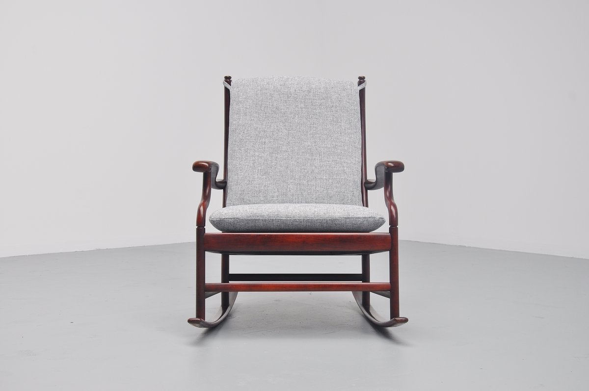 Very nicely shaped rocking chair in solid mahogany wood, Denmark, 1960. The chair is strongly attributed to the designs of Ole Wanscher, but I cannot find the right documentation. It seats very comfortable and is newly upholstered in light grey semi