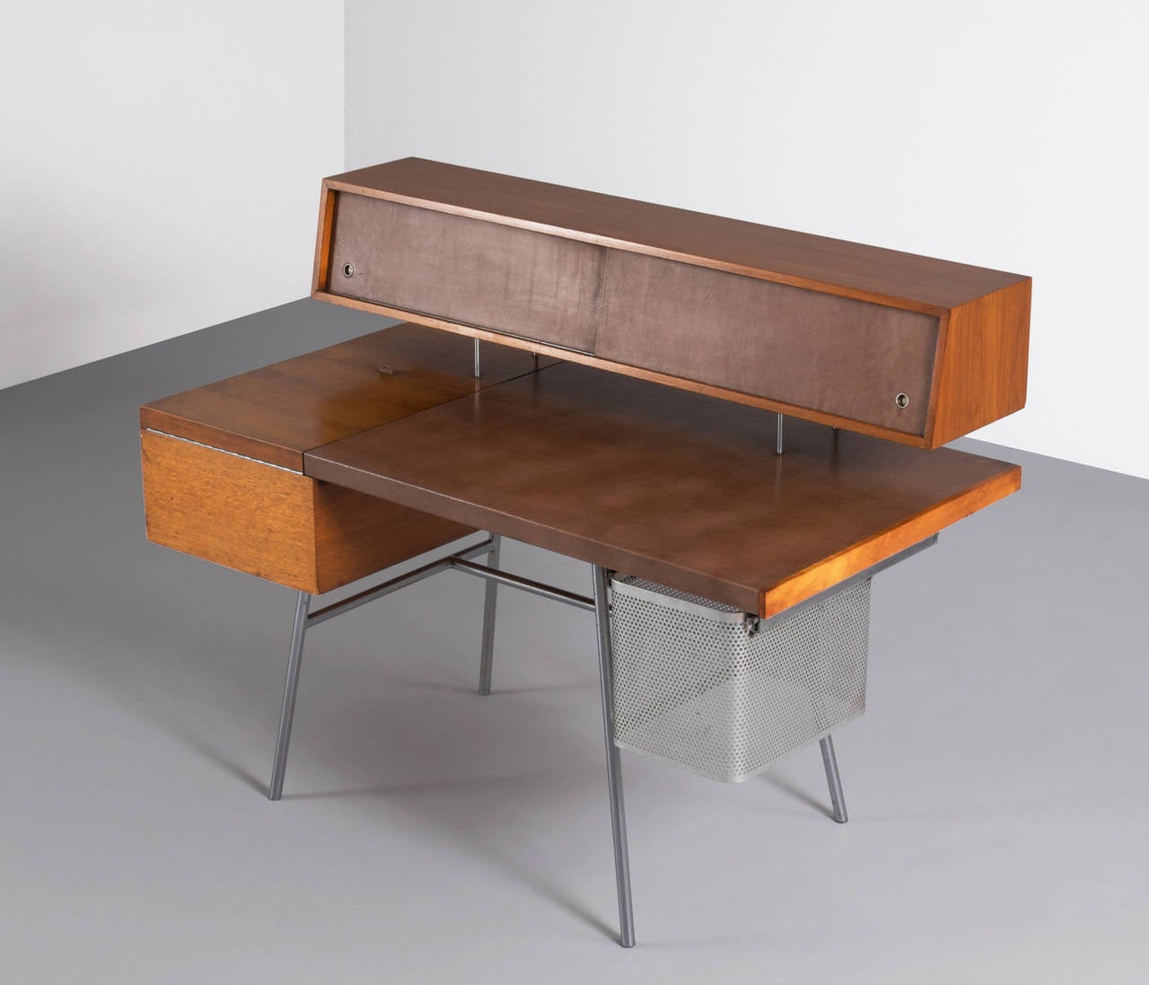 Rare Mid-Century George Nelson desk in walnut, original patinated leather, and a steel base designed in 1946.

The sliding doors, covered in leather, open to indicate the shelves and drawers. 
A accompanying perforated steel file cabinet which