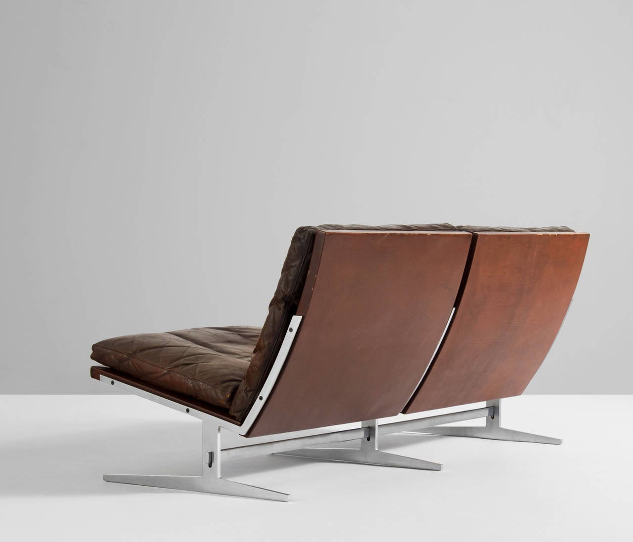 Set of a two seat sofa and accompanying lounge chair by Fabricius and Kastholm for BO EX in a original patinated natural brown leather.

Very tight design with nice brushed steel frame and down filled high quality brown leather cushions which