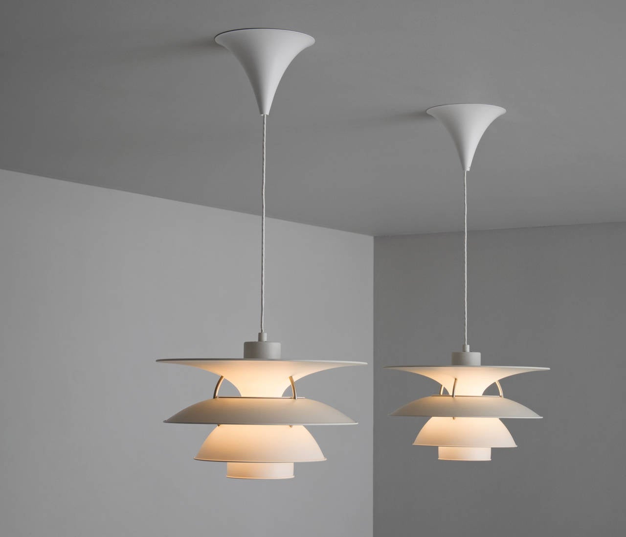 Set of two 'Charlottenburg' pendant lamps by Poul Henningsen for Louis Poulsen.

Four white metal shades mounted on three steel ribs.
The shades are designed for horizontal and vertical surfaces to indirectly illuminate a room. Provides a smooth,