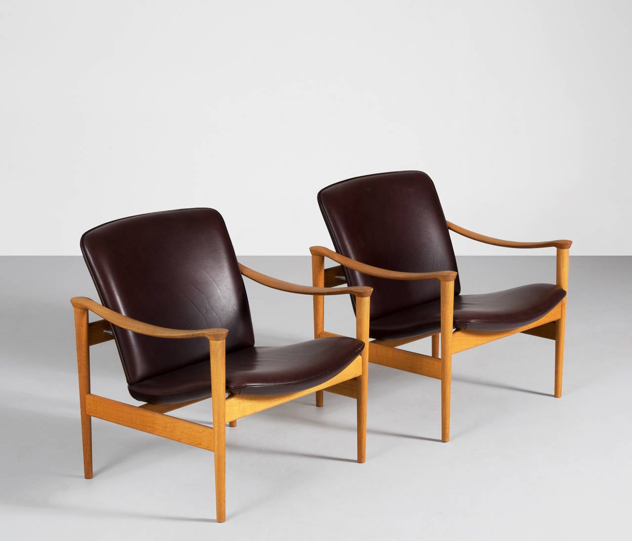 Real nice sculptural lounge chairs in oak designed by Frederik Kayser, Norway, 1960s. The chairs are upholstered in dark brown leather with a fabulous patina.

The shape of these chairs are very elegantly designed, also the comfort is really good