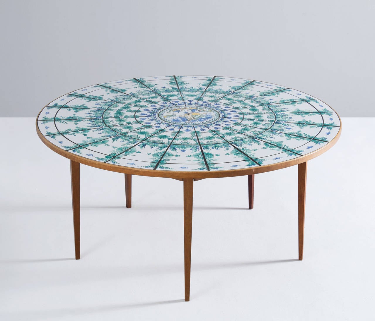 Bjørn Wiinblad round tiled dining table, hand-painted.

Beautifully detailed round dining table with very nice hand-painted tiles in the top. The white and green-blue colored inlaid tiles show nice floral decorative patterns. 
The top is rimmed
