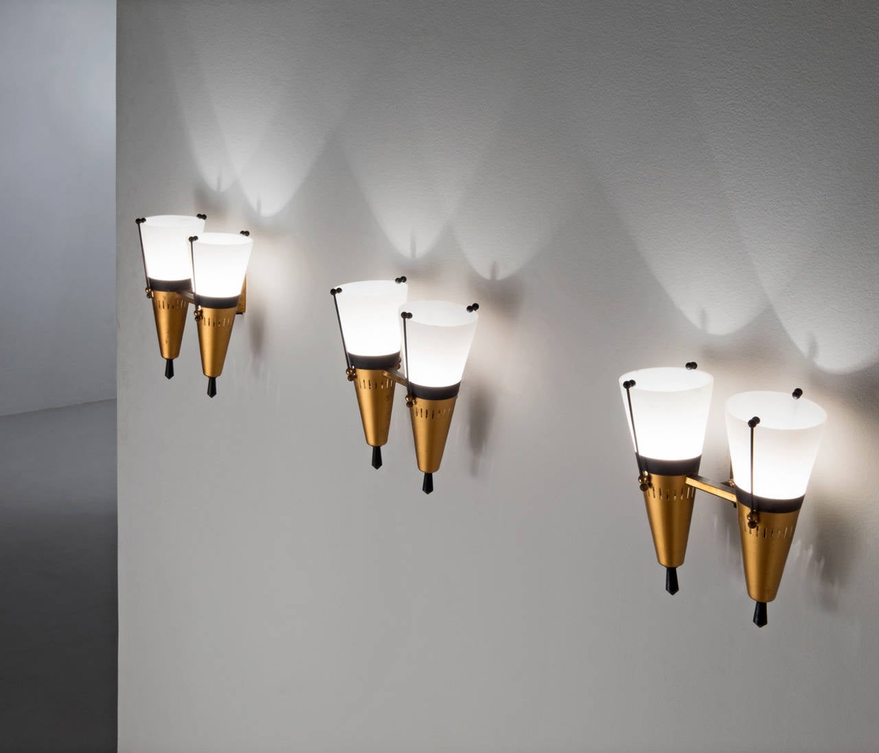 Set of three wall lights, in metal and glass, Italy, 1950s. 

Nice set of three matching duo wall lamps or sconces by Stilnovo. Frames are painted metal and the tops are equipped with a matte coated white glass to provide a very smooth