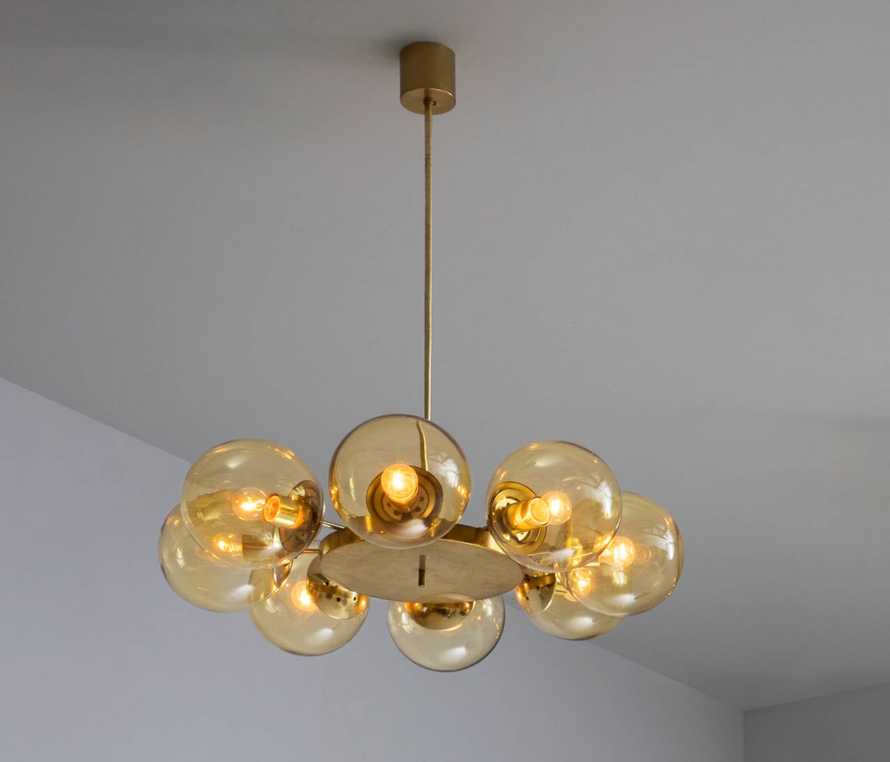 Large chandeliers with eight glass bulbs in brass.

The brass is nicely patinated and reflexes the light which creates a nice soft diffuse lighting, due to the gold yellow tinted bulbs. A warm ambient light for the surrounding space. Five items in
