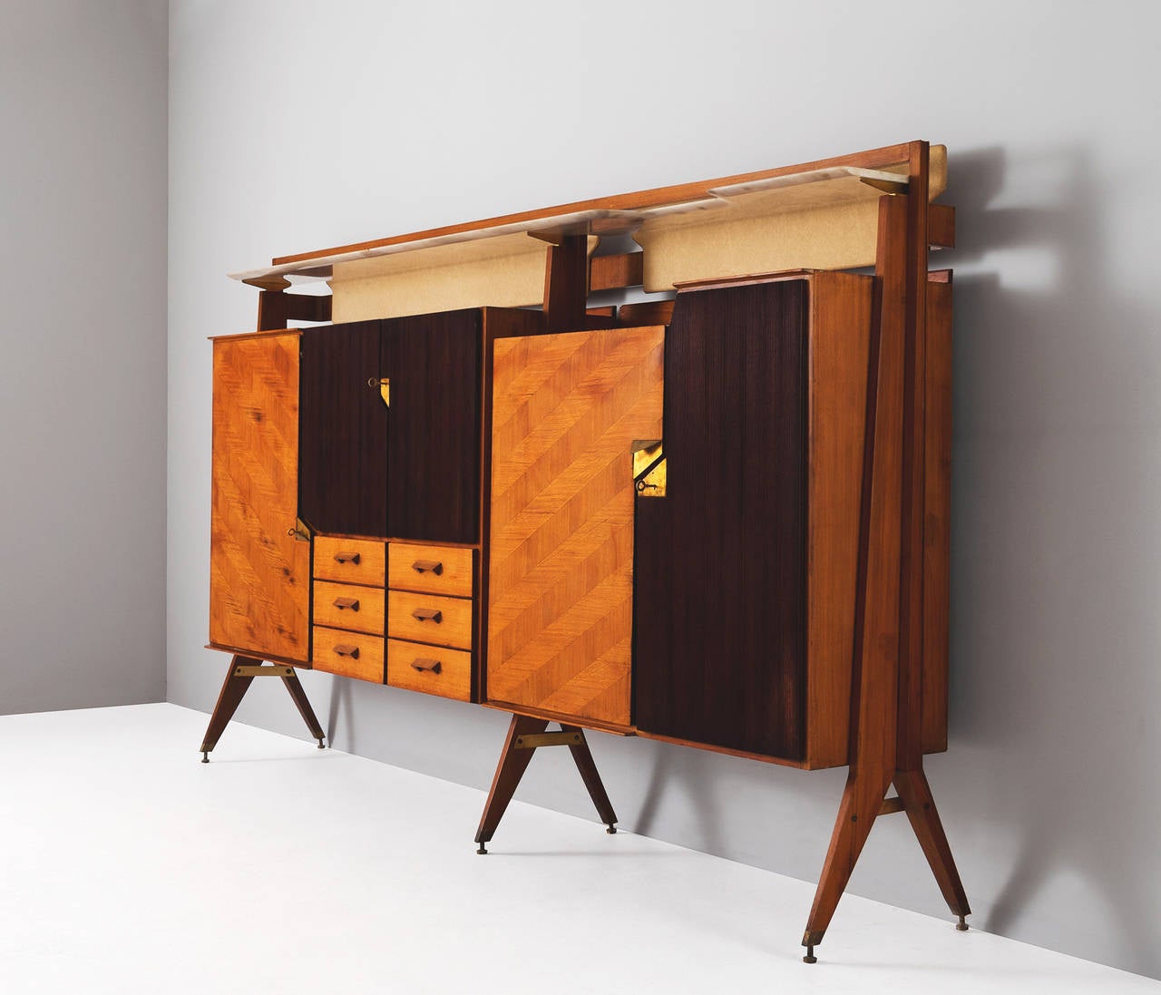 Italian wall console, Italy 1950s.

This expressive Italian cabinet is equipped with doors, drawers, shelves and a dry bar, all made out of high quality wood types.

The different doors and drawers are finished with either smooth, geometric