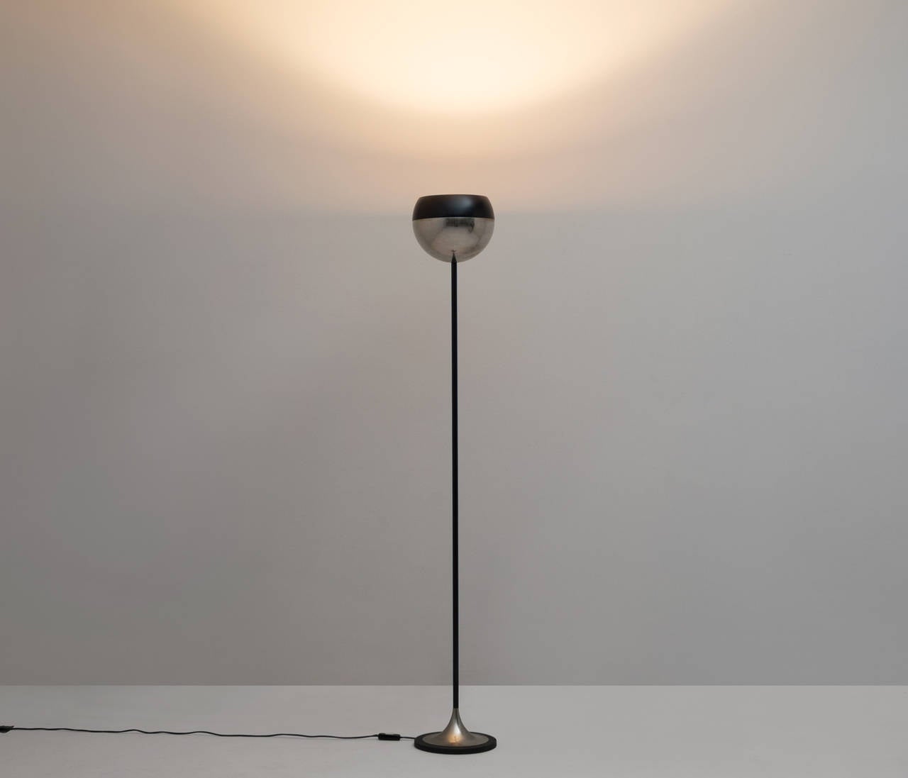 Stilnovo 'uplighter' floor lamp with a black lacquered steel stem and base, nickel plated details and a very nice, black rounded circle on top of the shade which contains the light socket. The cable runs nicely through the stem.

A very subtle and