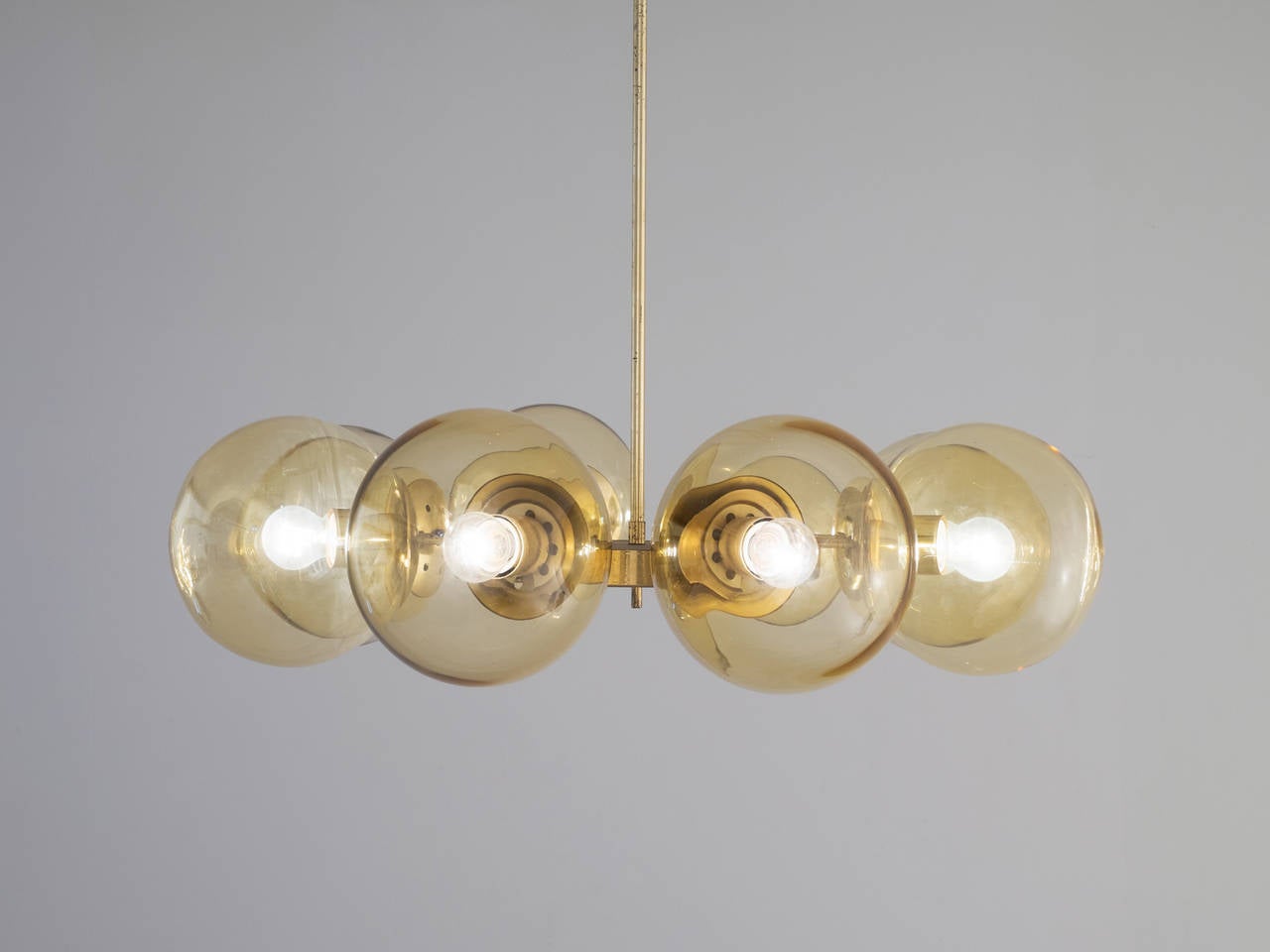 Large chandelier with eight glass bulbs in brass.

The brass is nicely patinated and reflexes the light which creates a nice soft diffuse lighting, due to the gold yellow tinted bulbs. A warm ambient light for the surrounding space. 
9 items