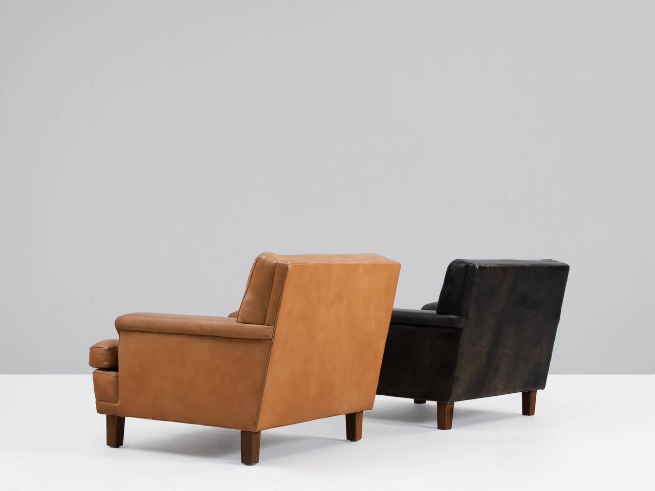 Pair of lounge chairs, in leather and wood, by Arne Norell, Sweden 1960s. 

Two lounge chairs designed by Arne Norell with wonderful shapes and comfort in cognac and black leather. The tufted leather cushions give these chairs an interesting