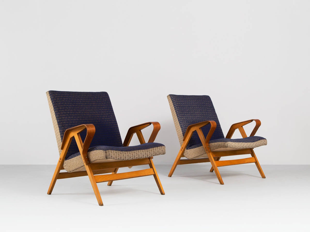 Early 1950s plywood lounge chairs. The chairs show modern shapes and elegant curves in the armrest. The seats float in between the legs and are covered in their original upholstery.

Please note that the fabric shows some signs of wear and use,