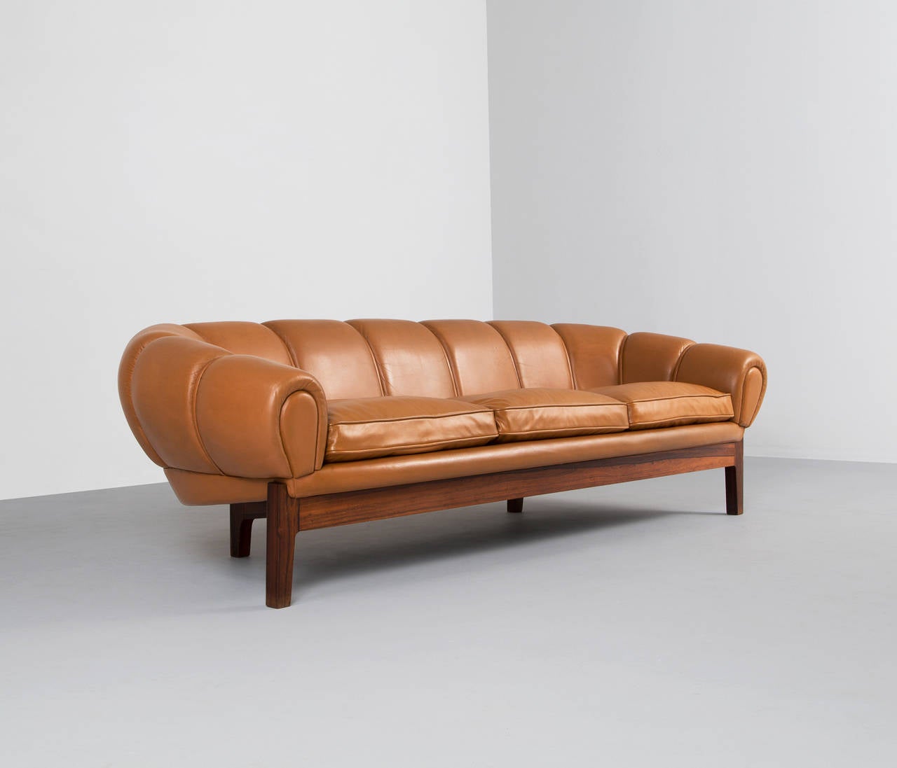 A highly unusual large sofa design attributed to Illum Wikkelsø, seating three persons. 

The sofa distinguishes itself by the round shapes, combined with the very low and flat profile, creating a very interesting expression. The use of the deep