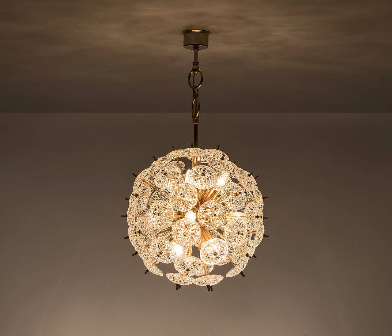 Sputnik chandelier with floral cut crystal glass elements and brass frame, for Val Saint Lambert, Belgium 1970s.

The basic shape of the fixture hides amazing details. A closer look reveals a stunning effect of the well-made glass elements, which