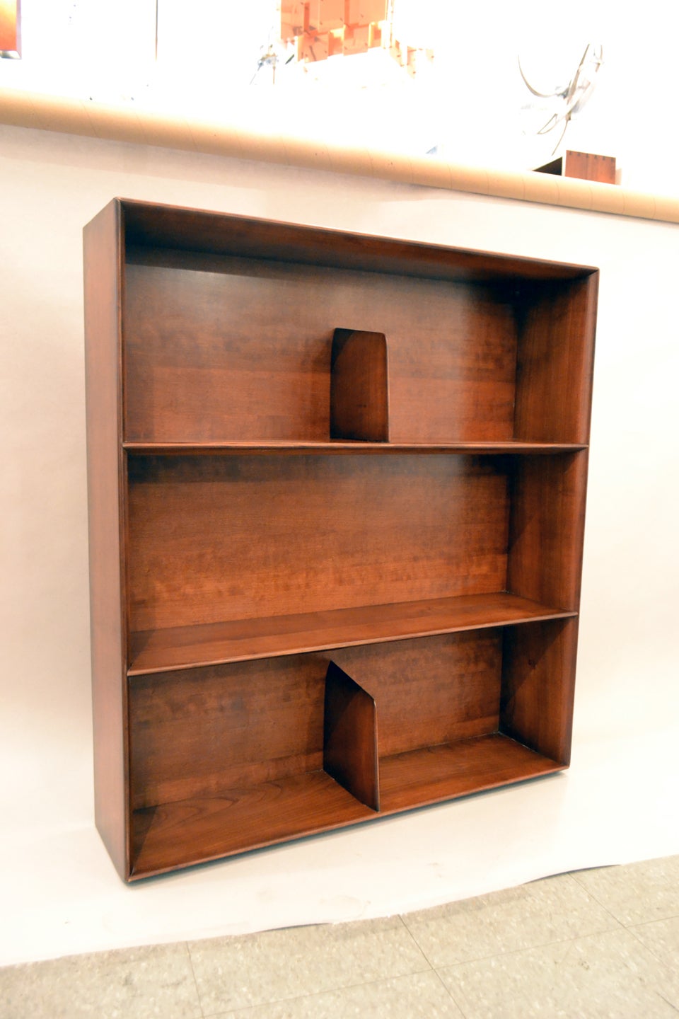 A wonderful modernist bookcase in walnut by Gio Ponti, Italy. The bookcase is designed to be mounted on the wall. The top and bottom shelves are divided by sculpted slivers of walnut.