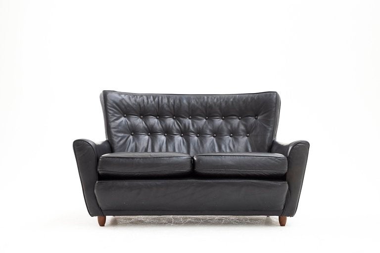 Real nicely designed Danish black leather two seater sofa in original upholstery. 

The sofa has a very elegant shape and due to the details in the upholstery, the sofa has a real unique expression.

The condition of the leather is still very