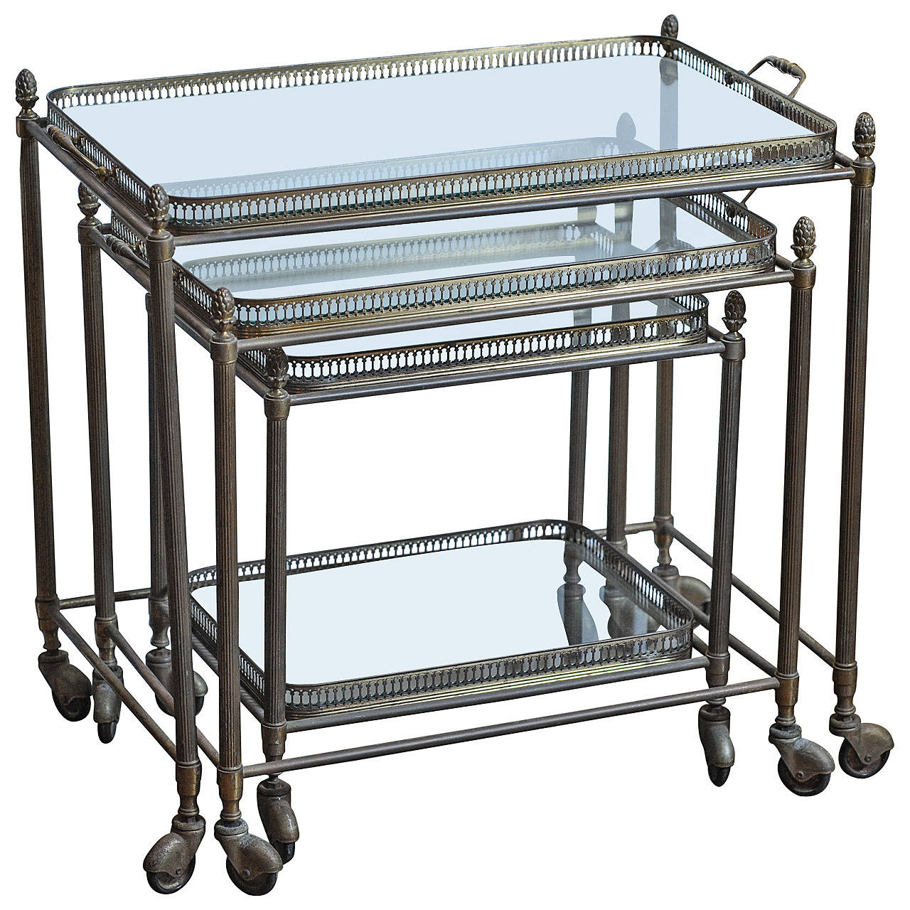 A set of three 1960s French brass nesting tables on wheels with glass