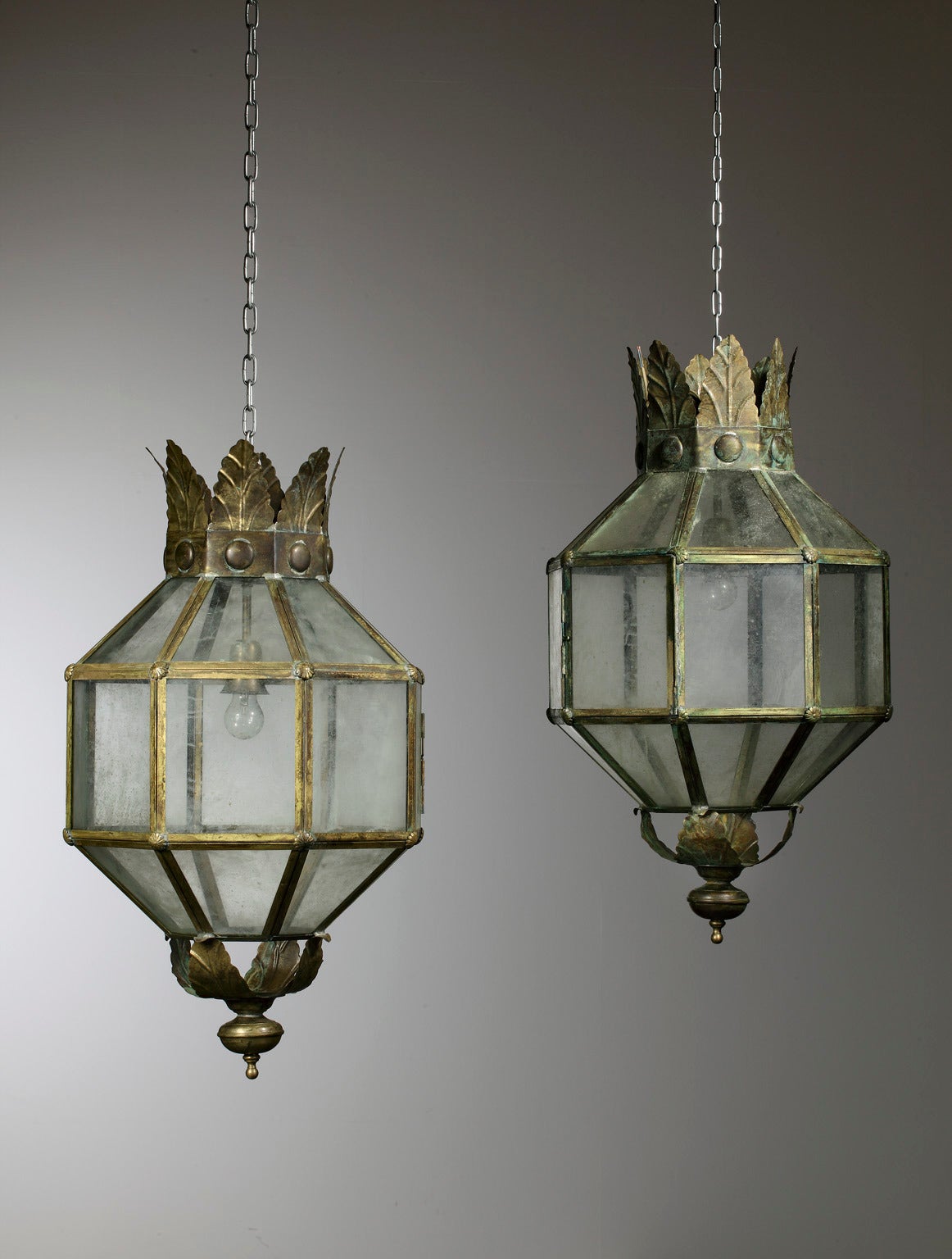 A pair of large aged copper and glazed octagonal section lanterns, each with pressed metal foliate cresting and waisted terminal, also available per piece.