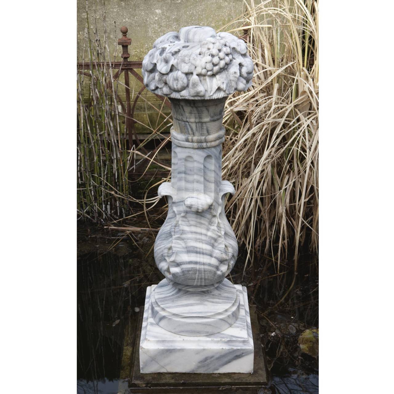 Modelled as an arrangement of flowers atop a fluted pedestal, with waisted socle and square base.