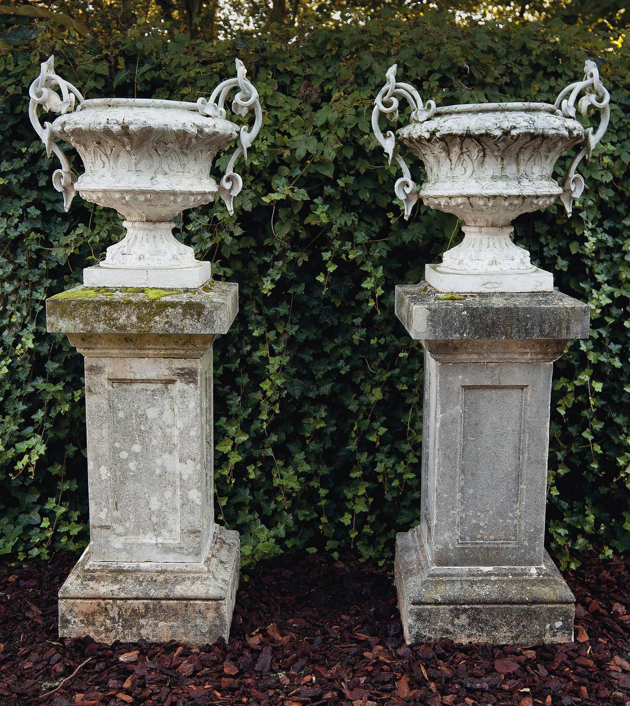 Large pair of French white painted cast iron twin handled urns or garden vases, 19th century, the scroll cast handles descending from the rims to the undersides, each stamped 'Les Freres Moral, Charlesville', 72 cm high, 75 cm wide. On associated