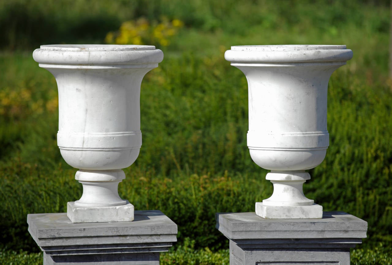 Pair of 19th century carved white marble garden urns each with knopped rim, waisted socle and square base.