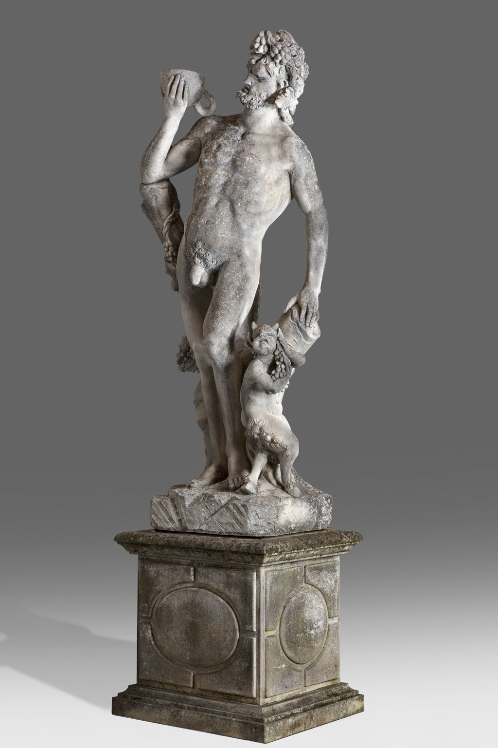 The God of wine portrayed nude and standing, a cup in his raised right hand, the infant satyr at his feet, on a rectangular section limestone plinth with moulded upper edges and base, the figure 250 cm. high, 350 cm. high overall.

It seems that