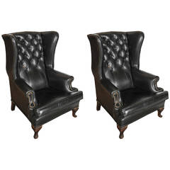 A pair of early 20th C. French black leather upholstered fauteuils / club chairs