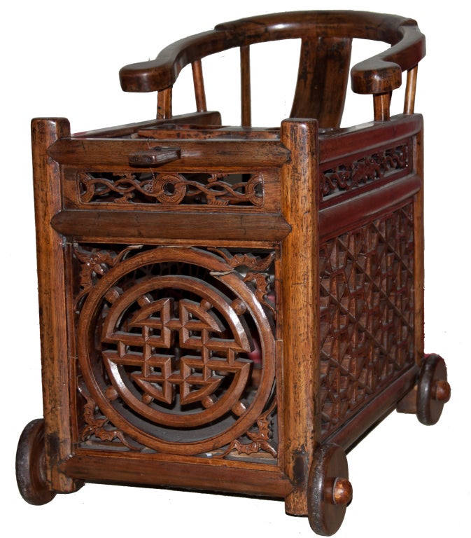 A baby minder with wheels, an antique cross between a baby carriage and a baby walker, ornamented with bats, symbolizing good fortune. This piece would be perfect as a plant holder, or in a room's corner.