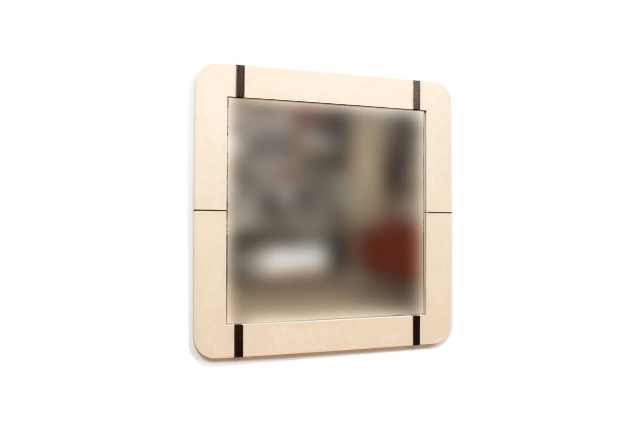 Large wall mirror in crackalured off-white lacquer with snakeskin and brass accents in the manner of Karl Springer.  This mirror's attractive square form with rounded corners and use of mixed materials lends itself to many varied interior settings.