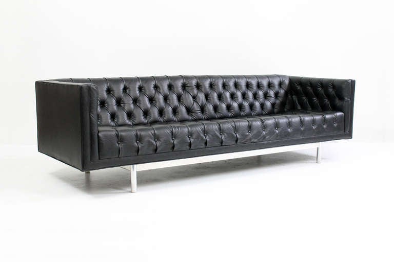 Jack Cartwright tufted sofa with polished aluminum base.  Well proportioned and comfortable chesterfield style sofa with attractive tufting in original black vinyl.  Signed with makers label to bottom decking.
