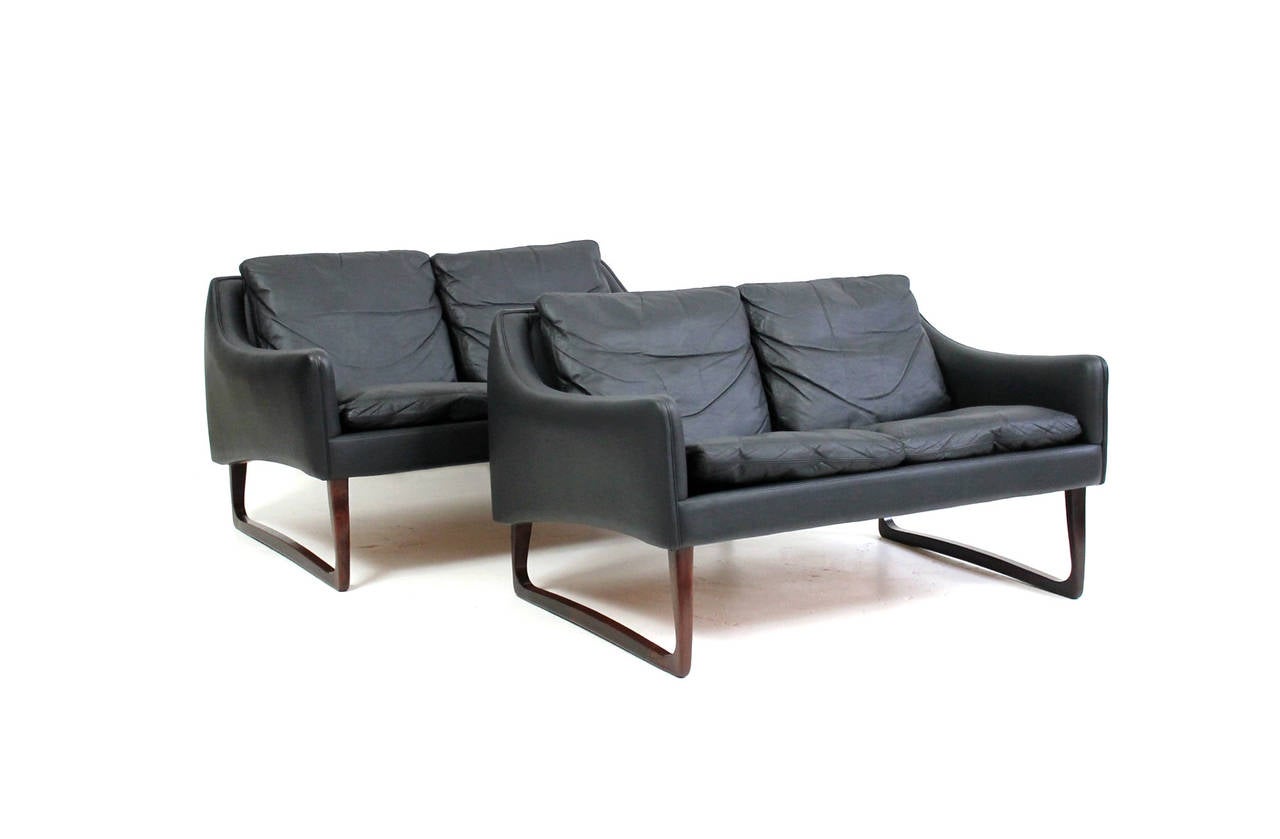 Exquisite pair of rosewood and black leather settees designed by Hans Olsen for CS Mobler, Glostrup. These settees feature a rarely seen leg variation with very sculptural and sinuous styling. Signed with the CS Mobler tag to the inside of one of