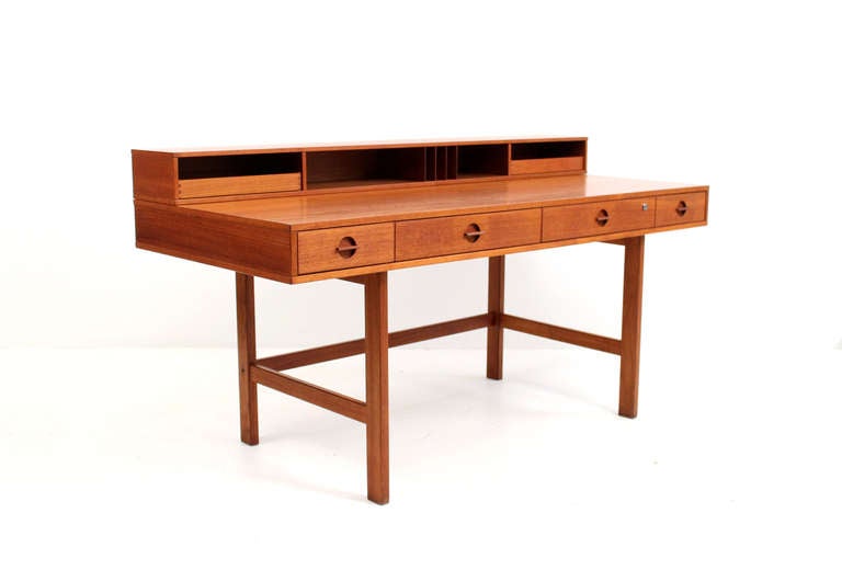 Danish teak designed by Peter Lovig Nielsen. Desk includes four larger drawers with two smaller pull out drawers and cubbies for storage on the top portion. The flipping top design of this desk enables this to transform into a partners desk.