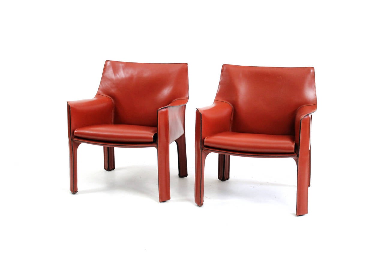 Pair of CAB lounge chairs by Italian designer Mario Bellini for Cassina. This vintage pair in near perfect condition is in a desirable red orange leather. Branded to underside and decking.