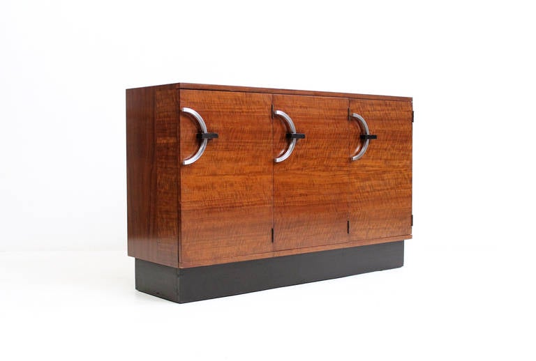 Early Art Deco Gilbert Rohde for Herman Miller cabinet from the East Indian Laurel line.  Cabinet features expressive graining and graphic stainless steel semi circular handles.  Interior drawers are cork lined as designed.  Rare cabinet from this